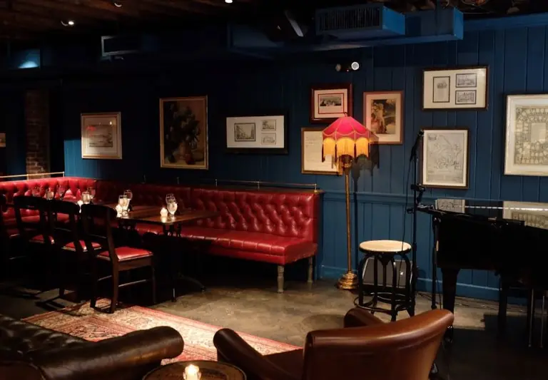 Fraunces Tavern's dining room: red leather banquettes, dark panelling hung with framed prints, and an upright piano.