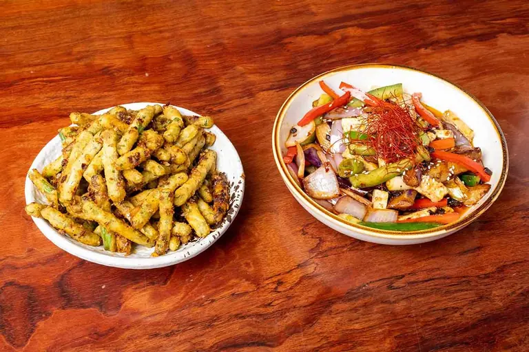 Two plates from Palette Tea House: crisp battered strips and a mixed vegetable dish, on a wooden table.