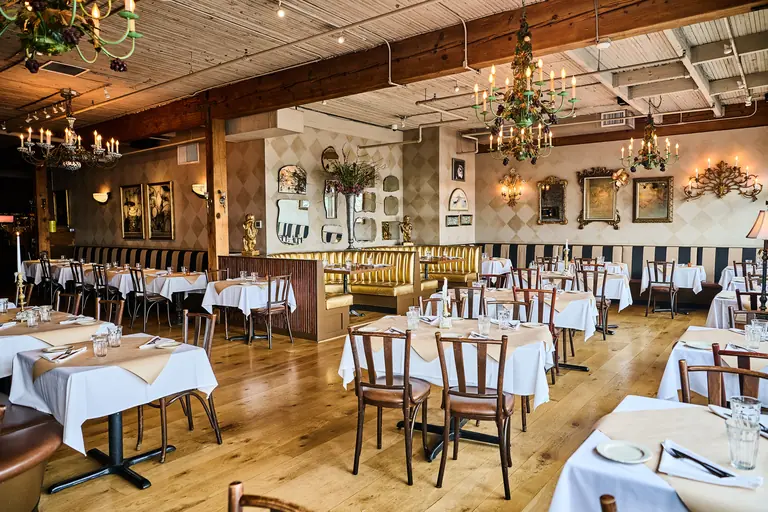 The Pink Door's dining room: white-clothed tables under a beamed ceiling, string lights and hanging greenery.