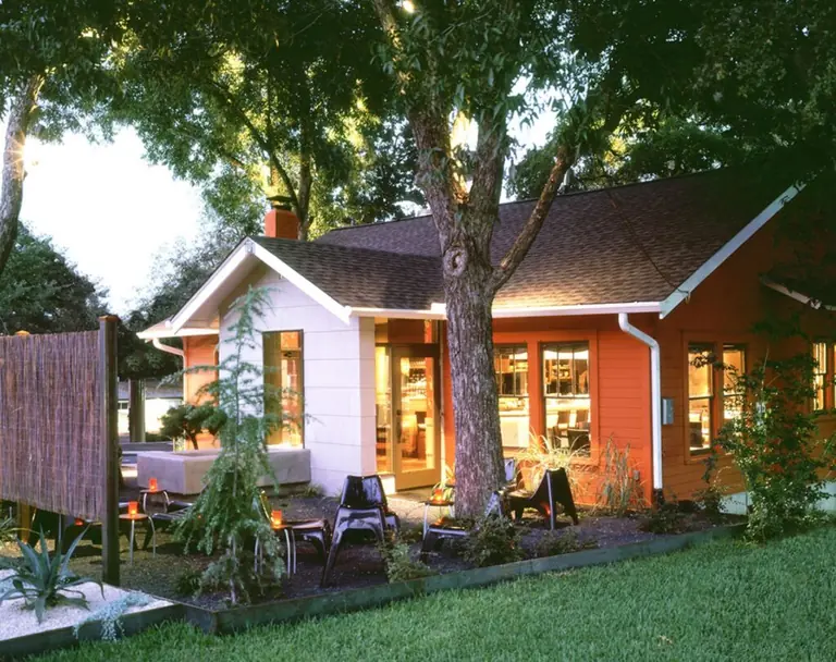 Uchi Austin from the street at dusk: a converted single-storey bungalow with lit windows, a patio and mature trees.
