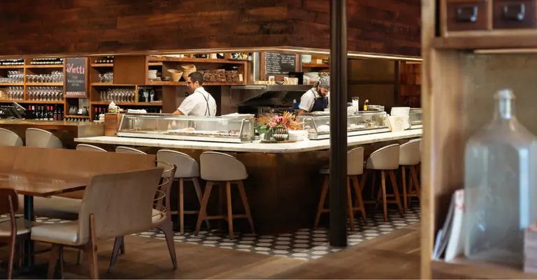 Uchi Dallas's dining room: a pale wood counter with place settings, seen past a shelf of glass bottles.