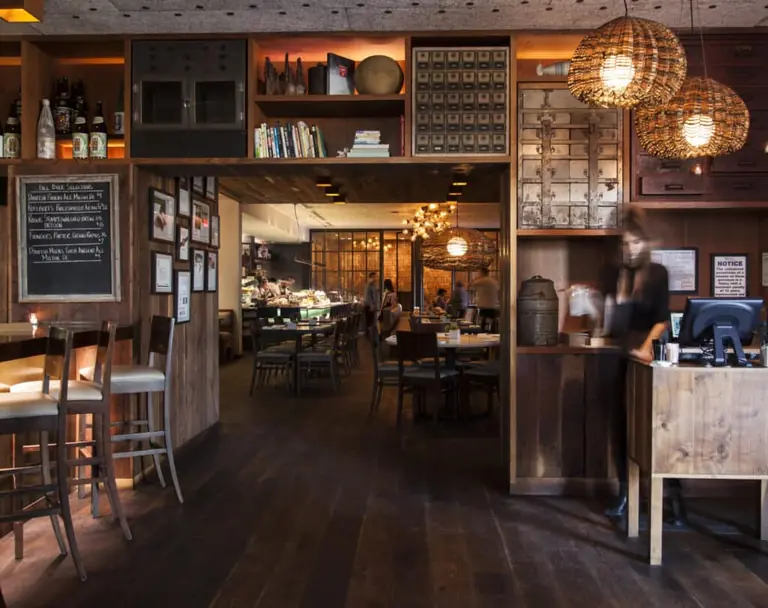 Uchiko's dining room: a lit bar counter under pendant lamps, with menu boards and stools.